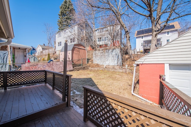 wooden deck featuring a residential view, fence, and an outbuilding