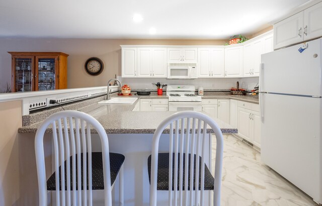 kitchen featuring marble finish floor, white cabinets, a sink, white appliances, and a kitchen bar