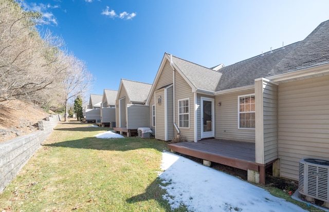 view of home's exterior featuring cooling unit, roof with shingles, a yard, and a wooden deck