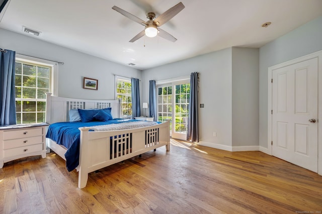 bedroom with a ceiling fan, wood finished floors, visible vents, and baseboards