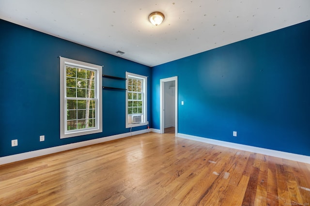 unfurnished room featuring cooling unit, baseboards, visible vents, and wood finished floors