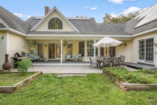 back of house with a patio, a yard, a chimney, and a vegetable garden