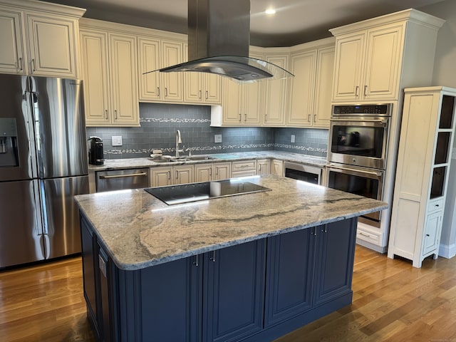 kitchen featuring wood finished floors, appliances with stainless steel finishes, island exhaust hood, and a sink