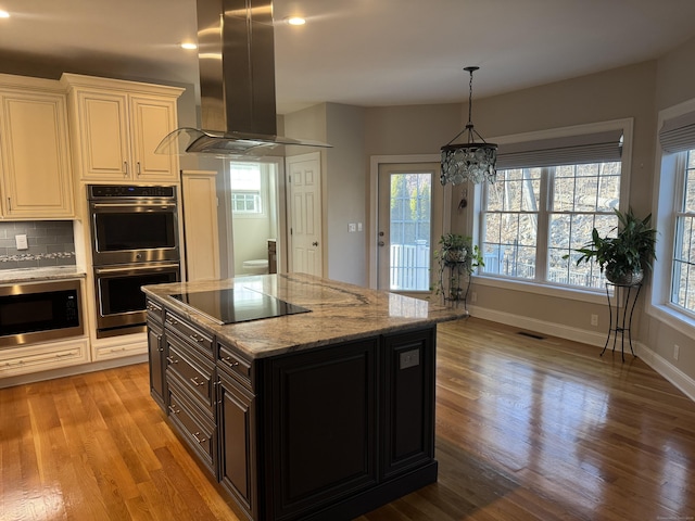 kitchen featuring backsplash, light wood-style floors, double oven, island range hood, and built in microwave