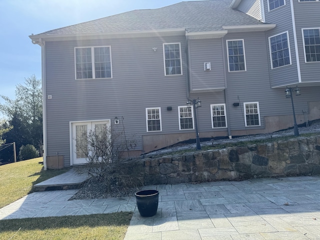 rear view of house with a lawn and roof with shingles