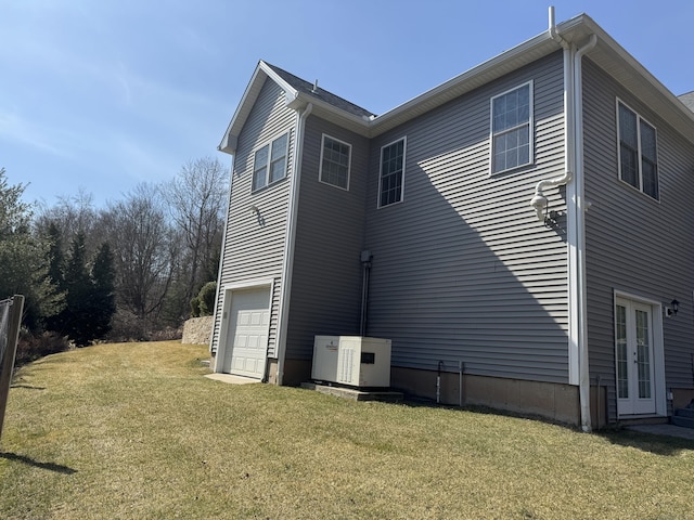 view of property exterior featuring a garage, a lawn, and french doors