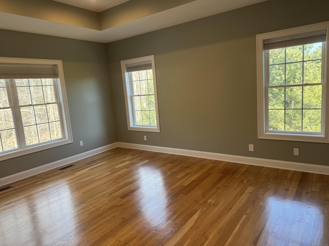 spare room with wood finished floors, baseboards, and visible vents