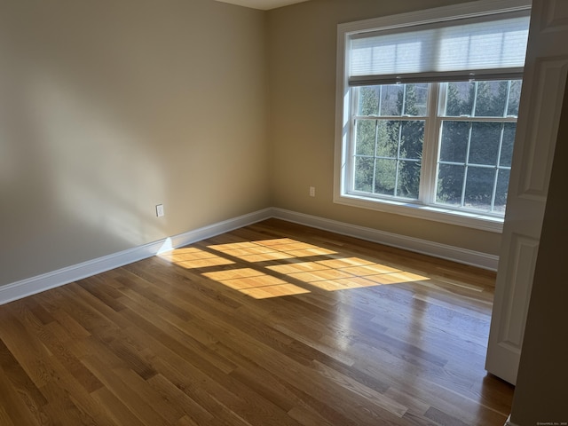 unfurnished room with dark wood finished floors and baseboards