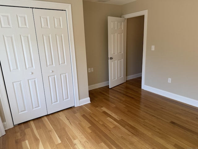 unfurnished bedroom with light wood-style flooring, baseboards, and a closet