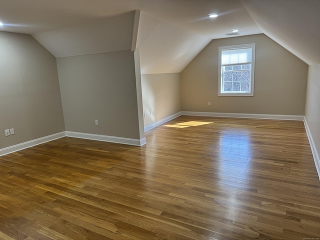 additional living space featuring dark wood-type flooring, baseboards, and vaulted ceiling