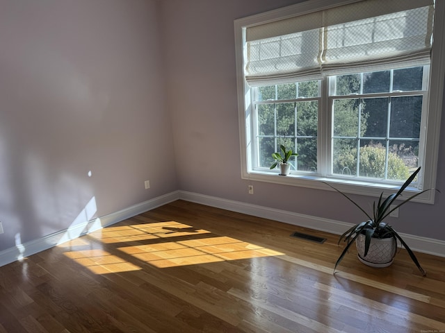 spare room featuring visible vents, baseboards, and wood finished floors