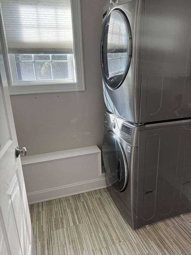 clothes washing area with stacked washer / drying machine, light wood-style floors, and laundry area