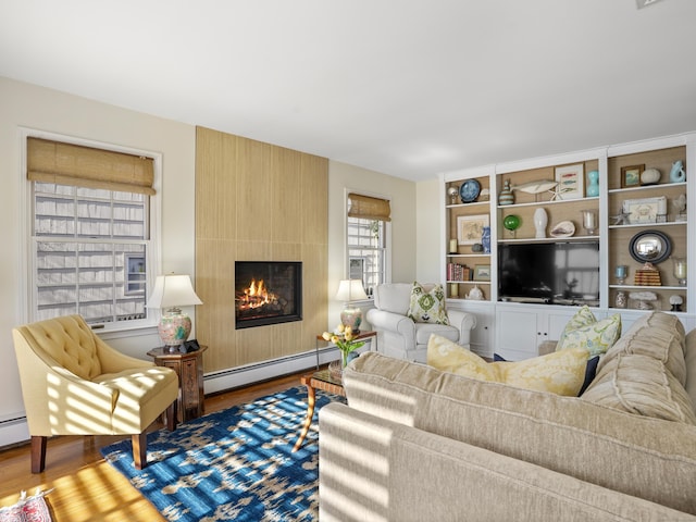 living room with a large fireplace, a baseboard heating unit, and wood finished floors