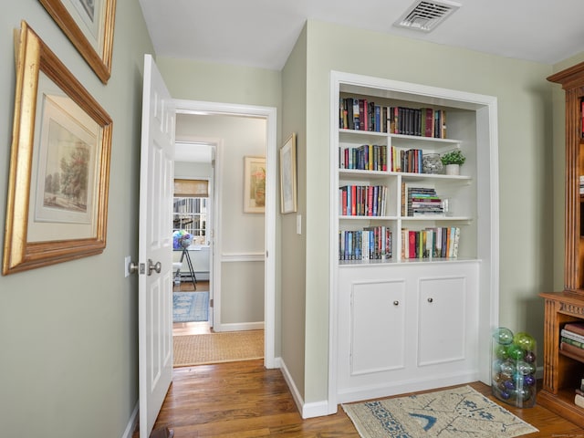 hallway with wood finished floors, visible vents, and baseboards