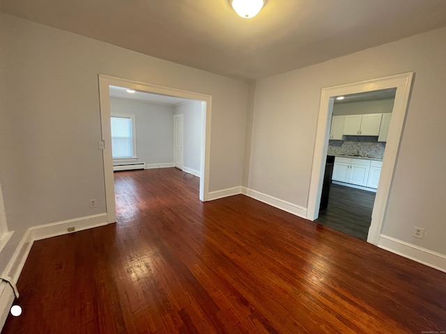 unfurnished room featuring a baseboard radiator, baseboards, and dark wood-style flooring