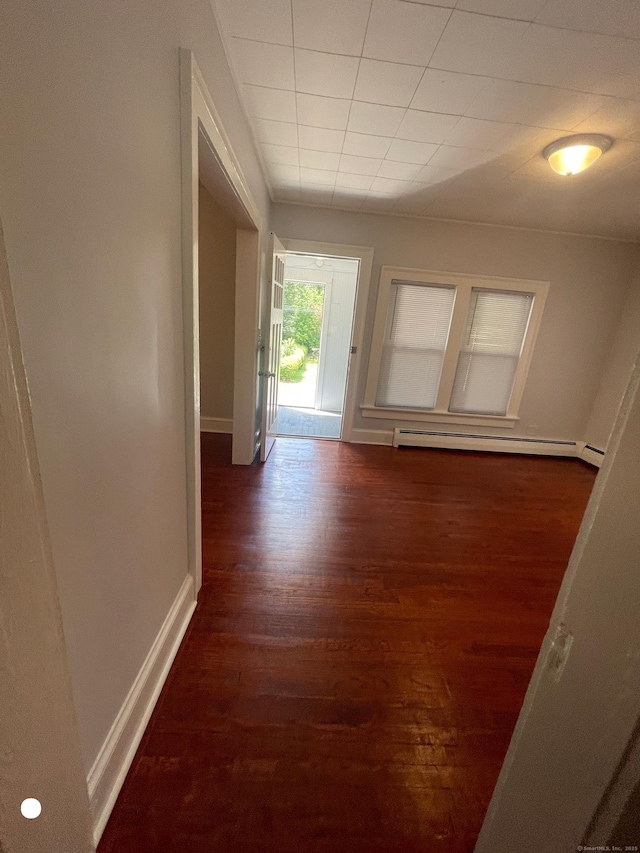 hallway featuring baseboards, baseboard heating, and wood finished floors