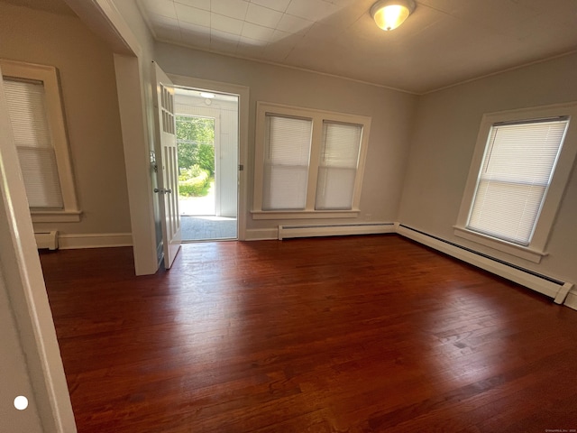 empty room with dark wood-type flooring, baseboards, and baseboard heating