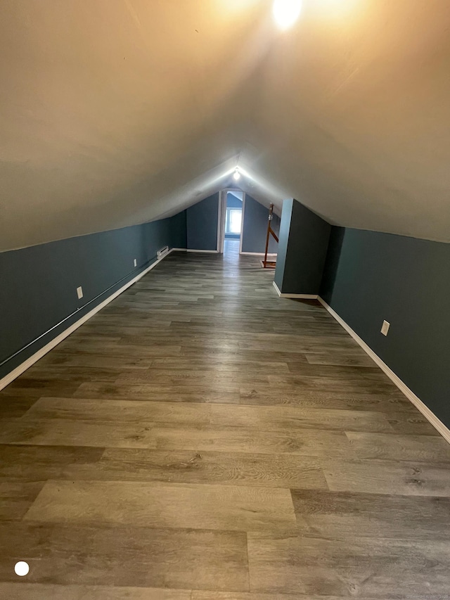 additional living space with lofted ceiling, dark wood-style floors, and baseboards