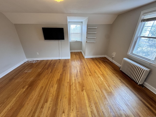 bonus room featuring baseboards, light wood-type flooring, lofted ceiling, and radiator