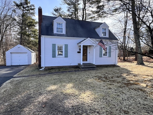 new england style home with driveway, entry steps, a detached garage, a chimney, and an outdoor structure