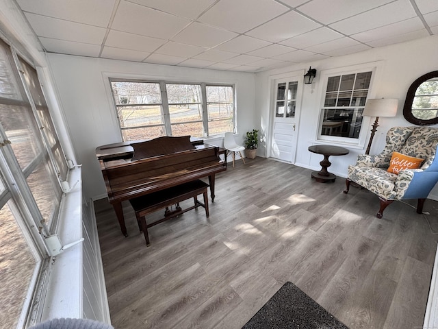 sitting room with a paneled ceiling, baseboards, and wood finished floors