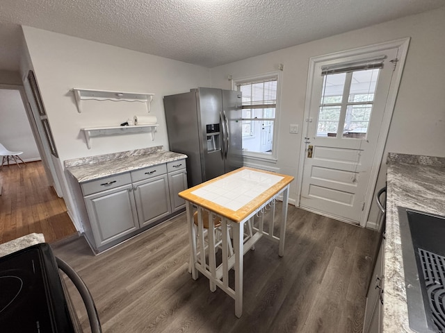 kitchen featuring stainless steel refrigerator with ice dispenser, light countertops, gray cabinetry, dark wood-type flooring, and black range with electric cooktop