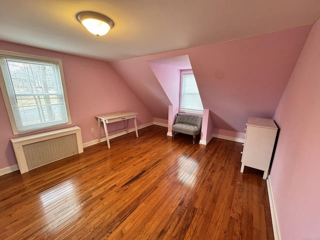 additional living space featuring vaulted ceiling, baseboards, hardwood / wood-style flooring, and radiator