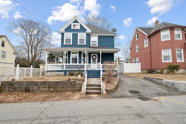 view of front of home with aphalt driveway, fence, a porch, and a shingled roof