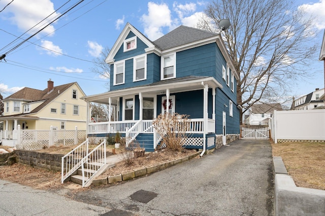 view of front of property with aphalt driveway, covered porch, a shingled roof, fence, and a gate