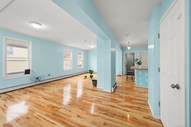 exercise area with a healthy amount of sunlight, baseboard heating, and wood finished floors