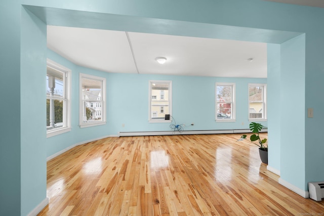 interior space with hardwood / wood-style floors, a baseboard radiator, and baseboards