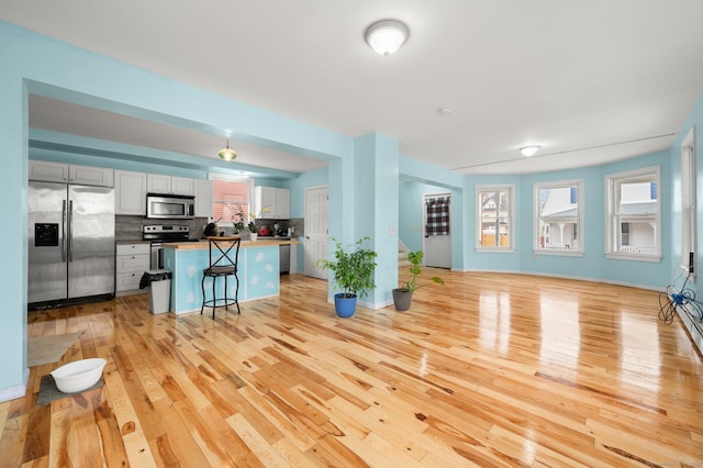 living room featuring light wood finished floors, a wealth of natural light, and baseboards