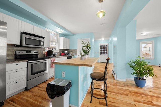 kitchen featuring stainless steel appliances, butcher block counters, white cabinets, and tasteful backsplash