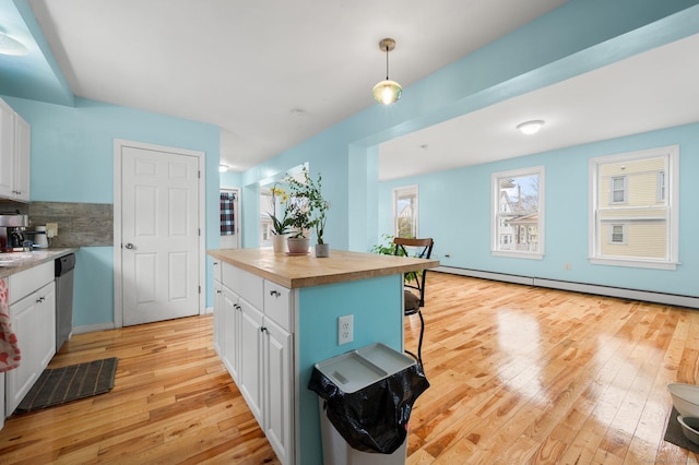 kitchen featuring white cabinets, butcher block counters, light wood-style flooring, a baseboard heating unit, and stainless steel dishwasher