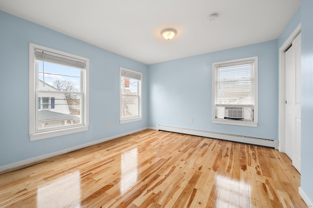 unfurnished bedroom featuring a closet, baseboards, baseboard heating, and hardwood / wood-style flooring