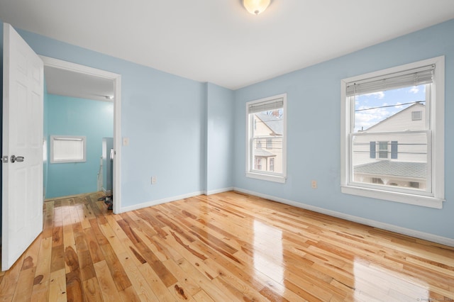 unfurnished room featuring plenty of natural light, baseboards, and wood-type flooring