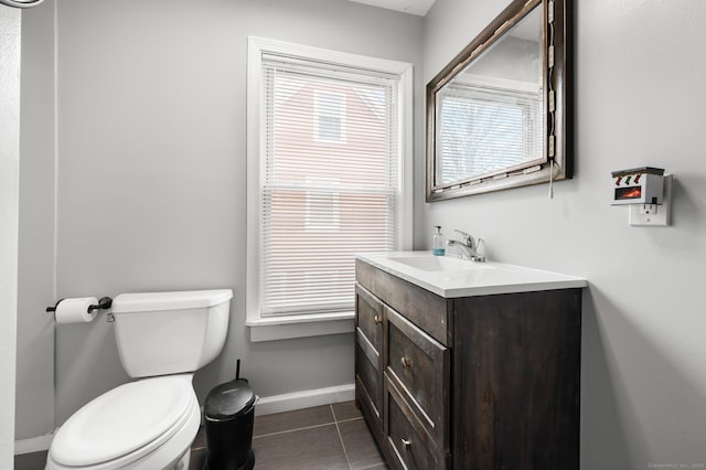 bathroom with toilet, tile patterned flooring, vanity, and baseboards