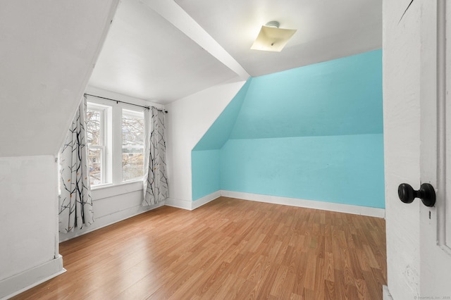 additional living space with lofted ceiling, wood finished floors, and baseboards