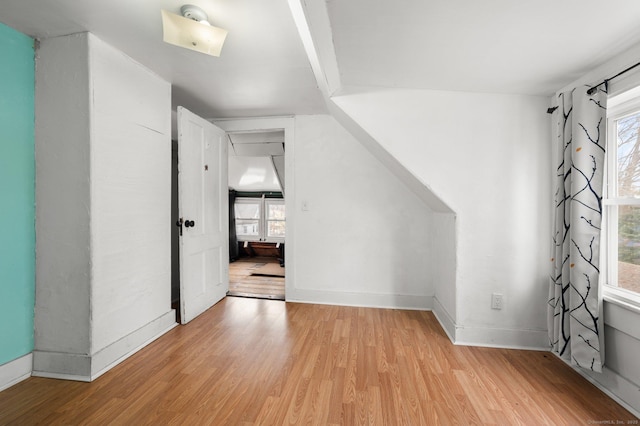 bonus room with plenty of natural light, light wood-style flooring, and baseboards