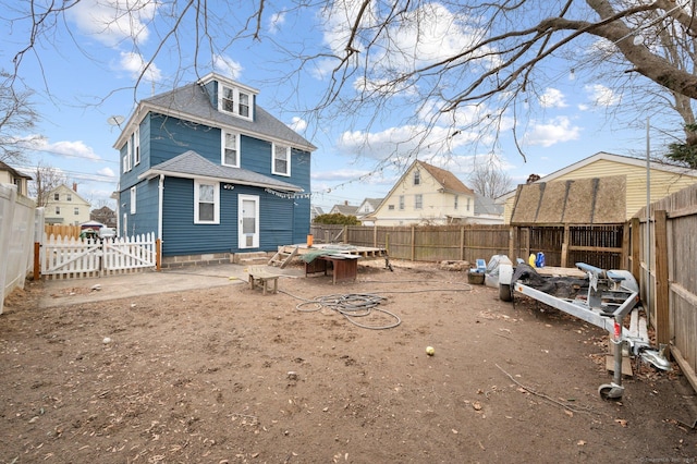 rear view of property with a fenced backyard, a gate, and roof with shingles