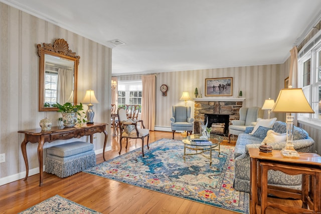 living area with wood finished floors, baseboards, visible vents, a baseboard radiator, and a fireplace