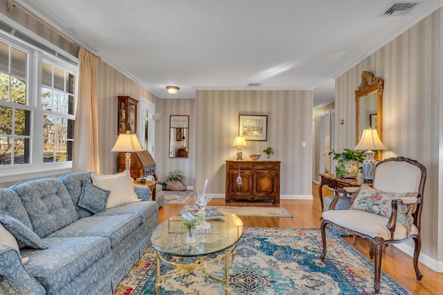 living room with visible vents, ornamental molding, baseboards, and wood finished floors