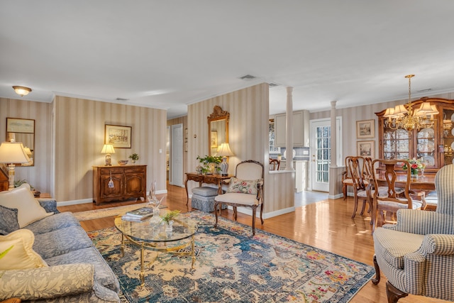 living room featuring decorative columns, wood finished floors, visible vents, and baseboards