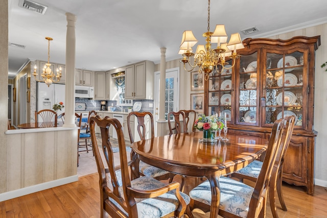 dining space featuring visible vents, an inviting chandelier, and ornate columns