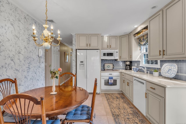 kitchen featuring wallpapered walls, light countertops, cream cabinets, white appliances, and a sink