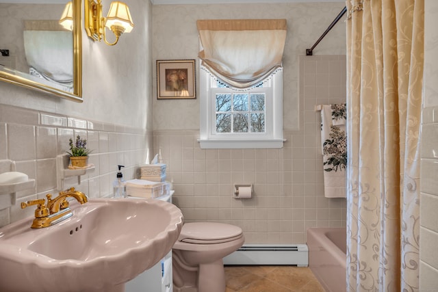 bathroom featuring tile patterned floors, a sink, tile walls, wainscoting, and baseboard heating