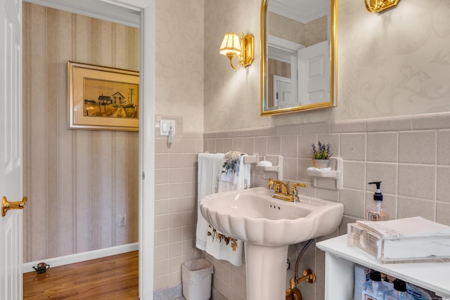 bathroom featuring a wainscoted wall, ornamental molding, wallpapered walls, and wood finished floors