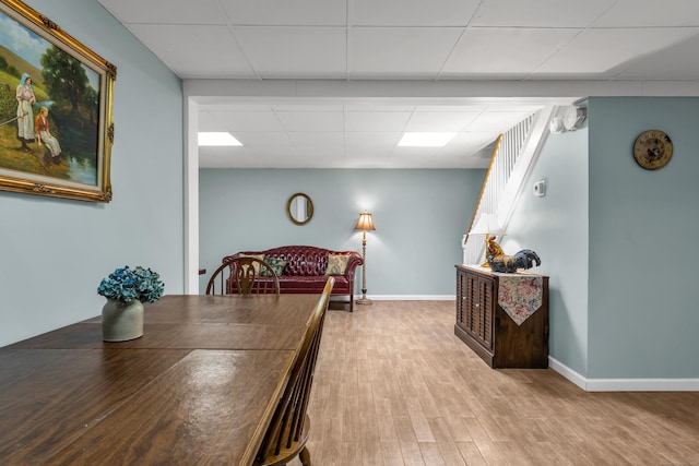 dining space with wood finished floors, a paneled ceiling, and baseboards