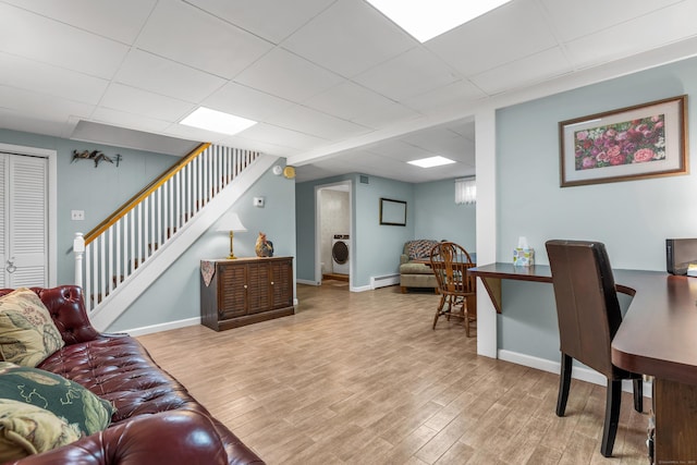 living area featuring baseboards, stairway, a drop ceiling, wood finished floors, and washer / clothes dryer