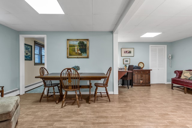 dining area featuring light wood-type flooring, a baseboard heating unit, and baseboards